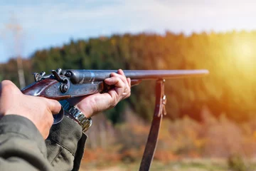 Photo sur Plexiglas Chasser Hunter with retro shotgun aims at the target. Hunting season