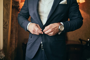 Businessman wears a jacket,male hands closeup,groom getting ready in the morning before wedding ceremony