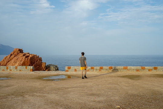 Young man walking towards the sea in Italy - shades of blue and orange