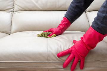 side view man cleaning leather sofa at home with wet towel