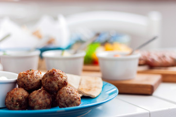 Fried meatballs with white sauce and flat cakes - traditional Greek lunch on a blue plate in a restaurant.