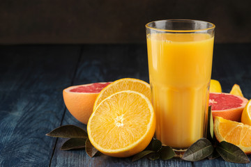 Citrus juices. Orange juice with fresh fruits on a blue wooden table. with space for text.