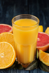 Citrus juices. Orange juice in a glass close-up with fresh fruit on a blue wooden table.