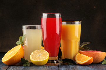 Citrus juices. Orange, grapefruit and lemon juice with fresh fruits on a blue wooden table.