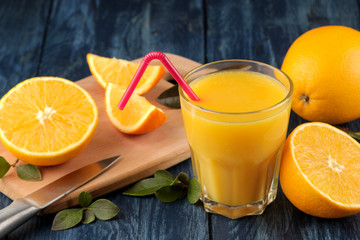 Citrus juices. Orange juice with fresh oranges on a blue wooden table.