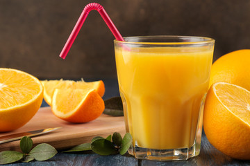 Citrus juices. Orange juice with fresh oranges on a blue wooden table.