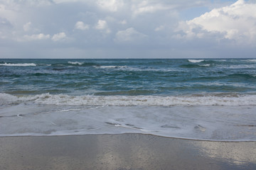 Waves crashing on shoreline with moody dramatic sky