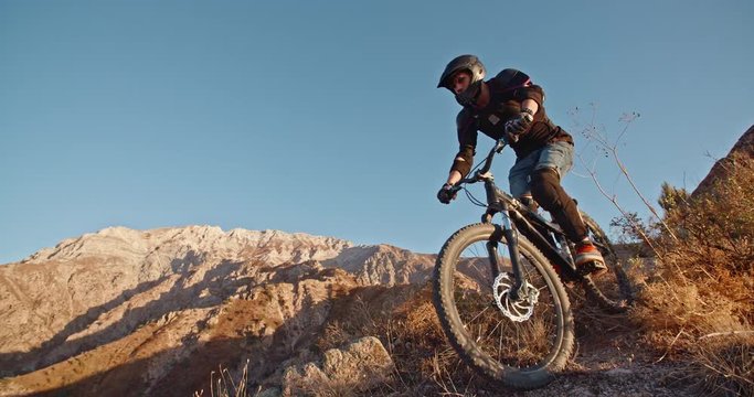 Cycler pedaling down the track in mountains during sunset, following the path, and getting away from it all 4k