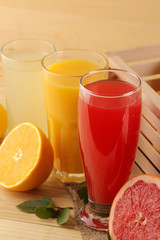 Citrus juices. orange, lemon and grapefruit juice with fresh fruits in a box on a natural wooden background