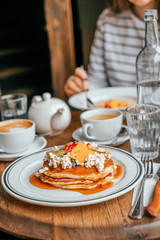 Perfect breakfast in the city cafe with pankakes, oatmeal, coffe and tea on the round wooden table.