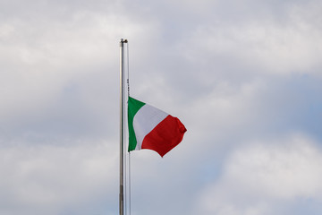 Italian tricolor at half mast against a cloudy sky