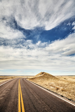 Retro toned picture of a scenic road in Badlands National Park, travel concept, South Dakota, USA.