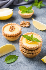 Homemade lemon curd in tartlets with fresh lemon and mint leaves.