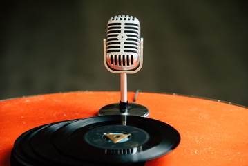 nostalgic image of a 50's microphone standing on an old orange table with old vinyl records