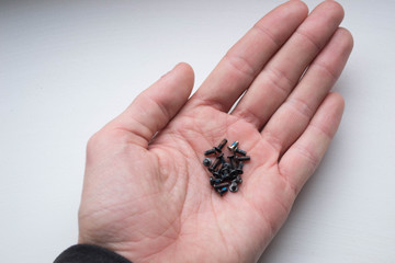 Group of black screws of the same size on a hand