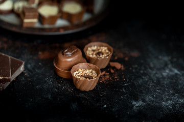 different, sweet pralines of dark, milk and white chocolate on a dark, wooden background