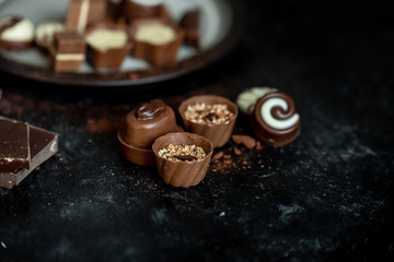 different, sweet pralines of dark, milk and white chocolate on a dark, wooden background