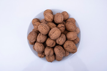top view of walnuts in a bowl isolated on white background