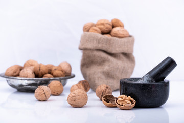 Walnuts in sack bag and plate, walnuts with nutcracker on isolated white background
