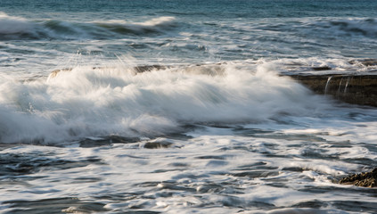 Rocky seashore with wavy ocean and waves crashing on the rocks