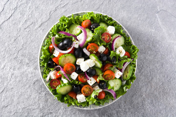 Fresh Greek salad in Plate with black olive,tomato,feta cheese, cucumber and onion on gray...