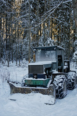 old plough tractor covered with snow in the forest
