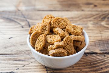 Croutons of grain bread with spices in the dishes. Wooden background.