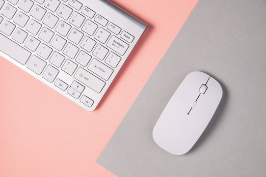Keyboard and mouse on a pale gray-pink background