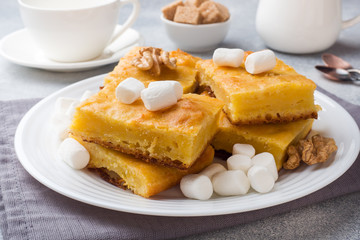 Pieces of delicious pumpkin pie with marshmallow and nuts on a plate.