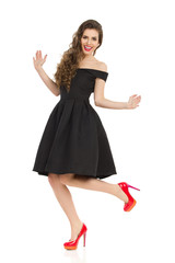 Excited Elegant Woman In Black Dress Is Dancing On One Leg