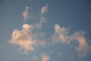 Beautiful clouds float across the blue sky. This background is illuminated by the natural light of heaven. Beautiful clouds and the sky are illuminated by bright light.