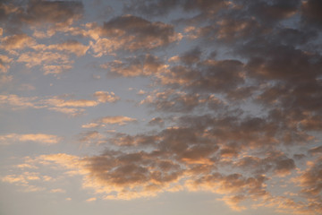 Sky background beautiful image. Abstract background is decorated with different types of clouds. Sunset in the evening sky. The sun  rays illuminate the clouds.