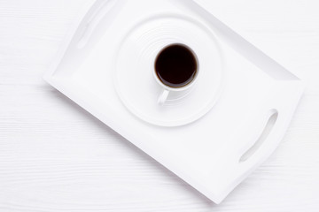 White cup of black coffee on a white wooden background. Copy space