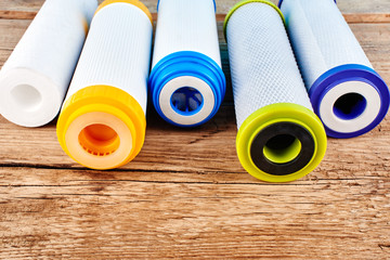 Water filters. Carbon cartridges on a wooden background. Household filtration system.