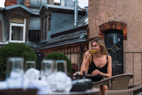 Young woman sitting on roof terrace drinking cup of coffee