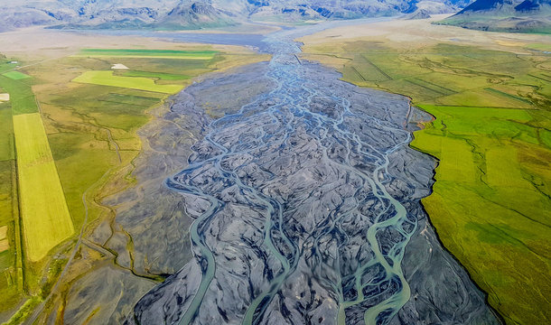 Southern Iceland aerial view of a river running towards the ocean through green fields