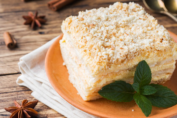 Fototapeta na wymiar Layered cake with cream Napoleon millefeuille vanilla slice with mint on wooden background.