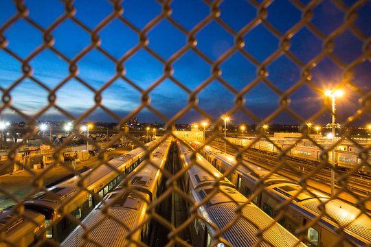Many trains seen through chain link fence seen from New York City train yard in Manhattan