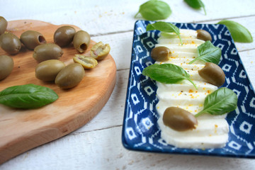 Mozzarella, green olives and basil leaves