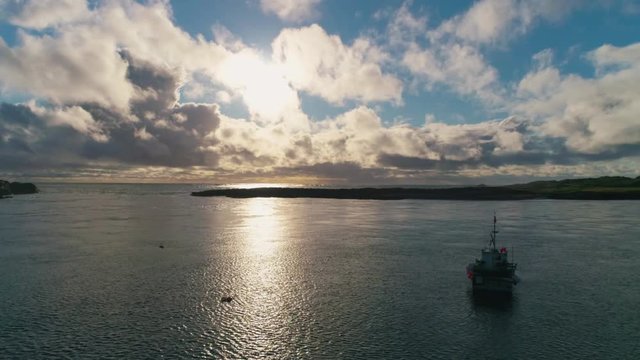 Stunning Aerial Drone Shot in Scottish Highlands, looking out to sunset at sea with one small fishing boat off Portnahaven bay on the Isle of Islay