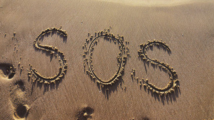 S.O.S written in the sand with a finger or stick