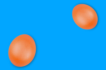 Pair of raw brown eggs on blue background with copy space for your text