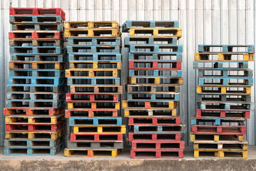 tacked of colorful rough wooden pallets background at cargo, warehouse.