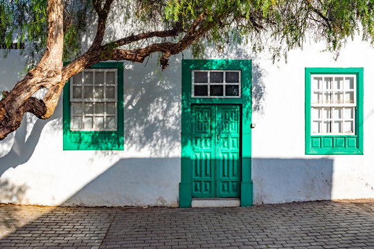Typical tiny Canarian house with cactus garden and green doors or windows on the island of Lanzarote, Teguise, Canary Islands, Spain