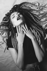 An unusual young woman with false braids lies on the floor. Black and white