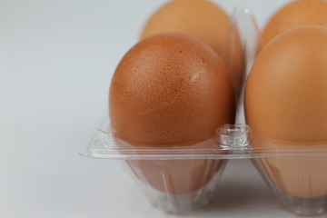 Close-up view of raw chicken eggs in egg box on white white background
