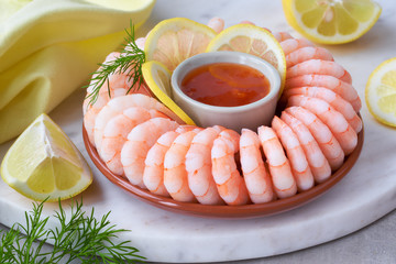 Close-up on shrimp ring with sweet chili sauce on marble serving board with yellow towel