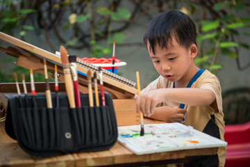 Young boy painting watercolor in the garden
