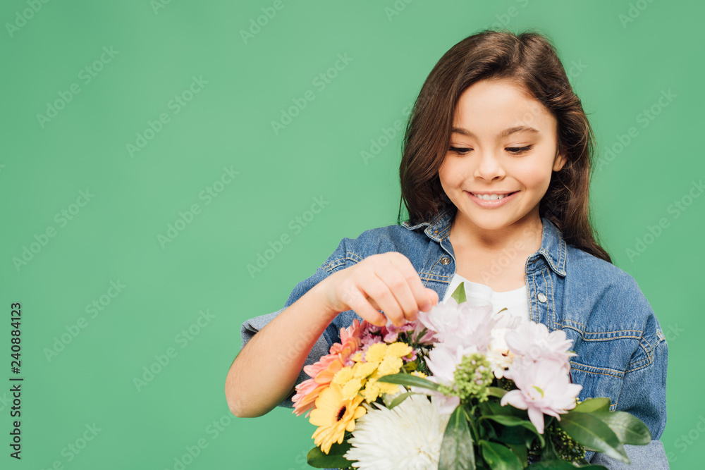 Wall mural adorable smiling child with flower bouquet isolated on green