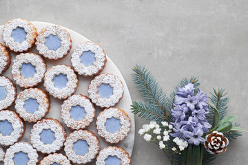 Fototapeta na wymiar Flower Linzer cookies with blue glazing on light concrete decorated with blue hyacinth flowers, fir twigs and herbs